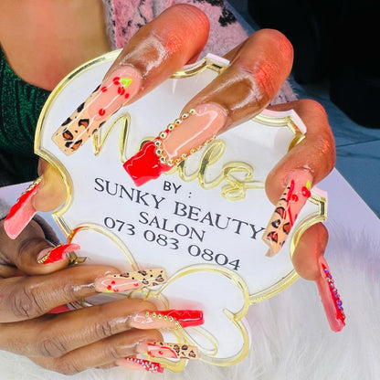 Close-up of hands with colorful nail art holding a sign for Sunky Beauty Salon.