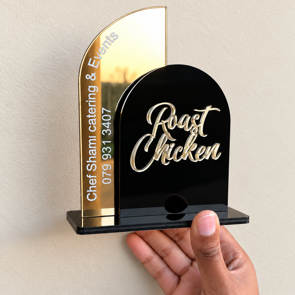 Black and gold double panel menu stand held in a hand to show its compact size